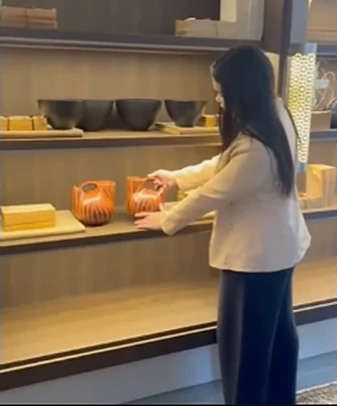 Kaylane organizando peças decorativas em uma estante de marcenaria planejada.